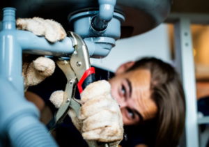 Engenheiro hidráulico profissional utilizando chave de grifo para manutenção e desentupimento de tubulação residencial em Alphaville.