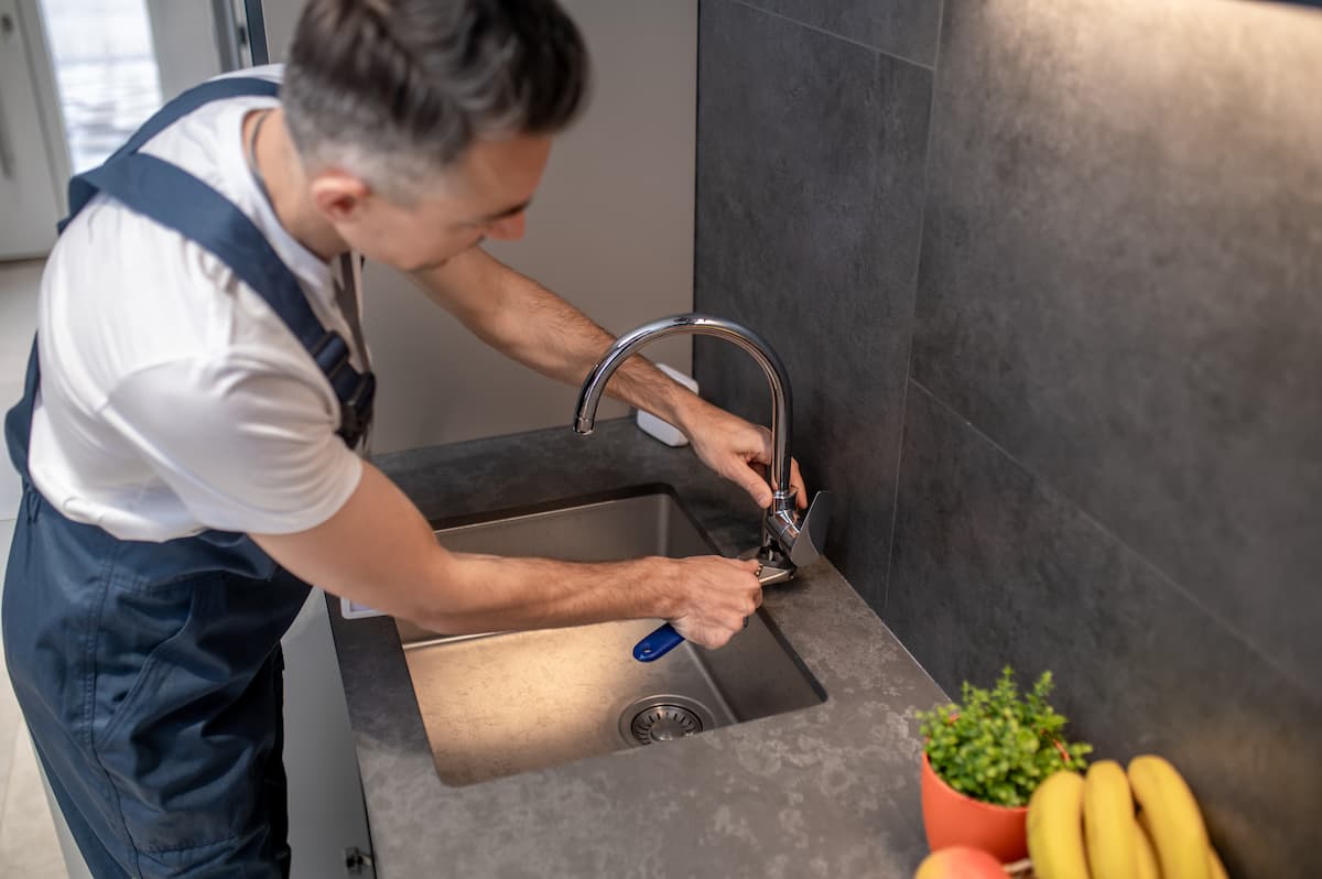 desentupidor mexendo na torneira da cozinha com alicate